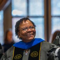 Woman reaches out to guests next to her smiling
